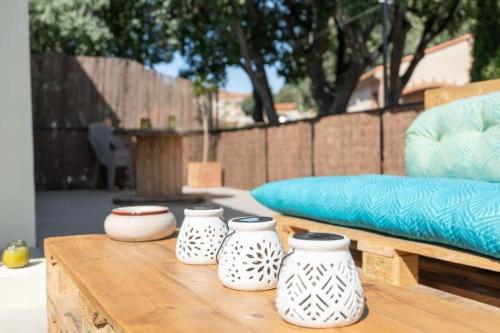 three white vases on a wooden table next to a couch at Appartement rénové, charme naturel et authenticité au cœur du village in Sorède