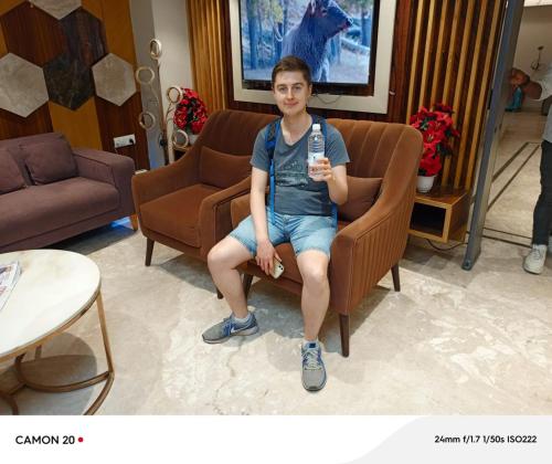 a young boy sitting in a chair holding a remote control at Hotel Glitz - Walk in from New Delhi Railway Station in New Delhi