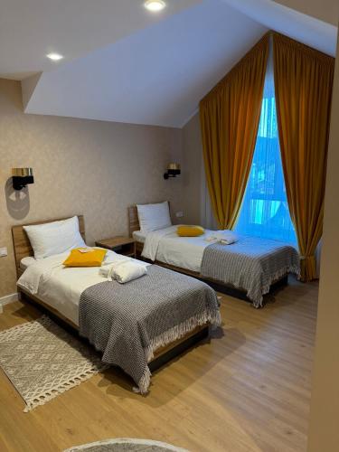 a bedroom with two beds and a large window at Guest House Zatyshnyi Dvir in Bukovel