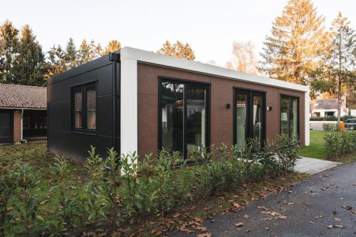 a small black and white house on the side of a road at Tiny House 'Het Berkenhuisje' in Voorthuizen