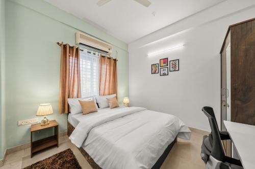 a white bedroom with a bed and a desk at Susan Grand penthouse in Bengaluru