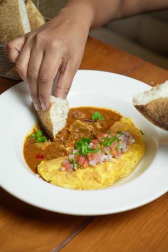 a person is eating a piece of food on a plate at Fairfield by Marriott Goa Anjuna in Anjuna