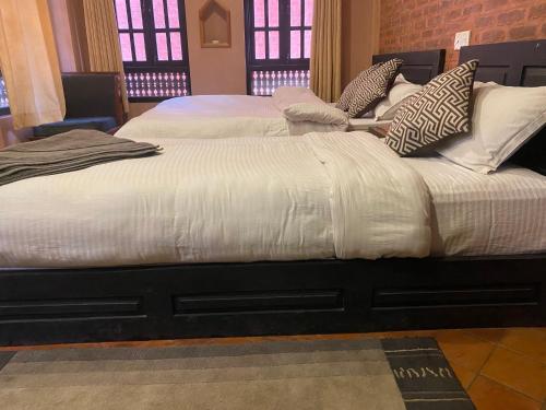 two beds with white blankets and pillows in a room at Bhaktapur Boutique Hotel and Restaurant in Bhaktapur