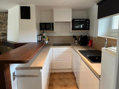 une cuisine avec des armoires blanches et un comptoir dans l'établissement Appartement neuf pour 2 personnes, à Quévert