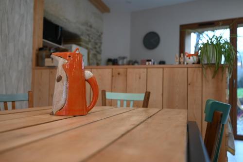 an orange mug sitting on top of a wooden table at Le Grenier - Chambre d'hôtes in Thusy