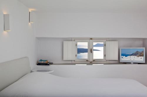 a white bedroom with a bed and two windows at 1809 Villa in Fira