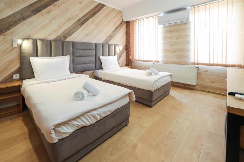 two beds in a room with wooden walls and wood floors at Family Hotel Gotse Delchev in Gotse Delchev
