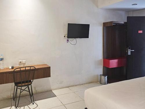 a bedroom with a desk and a tv on the wall at Urbanview Hotel Anata Inn in Pamanjengang
