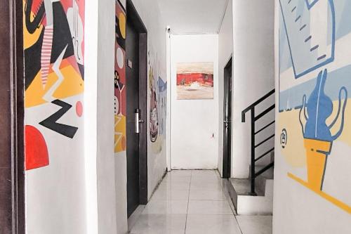 a hallway with colorful paintings on the walls at Urbanview Hotel Anata Inn in Pamanjengang