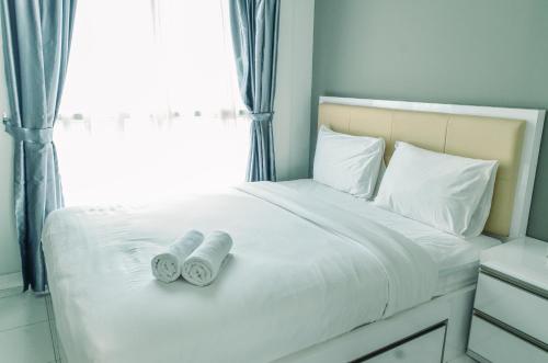 a bed with two towels on it with a window at Homey and Comfy 1BR at Casa de Parco Apartment By Travelio in Tangerang