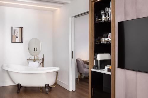 a bathroom with a bath tub and a television at Gran Hotel Inglés - The Leading Hotels of the World in Madrid