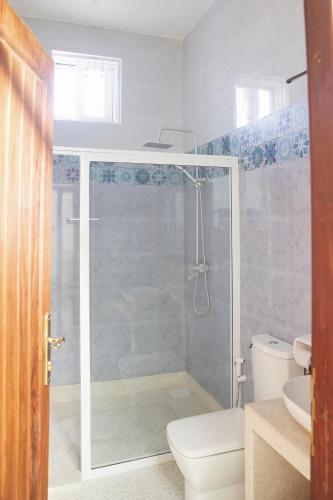 a bathroom with a shower and a toilet and a sink at Paje White House in Paje