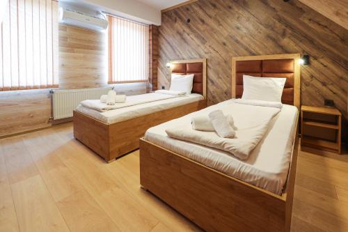 two beds in a room with wooden walls at Family Hotel Gotse Delchev in Gotse Delchev