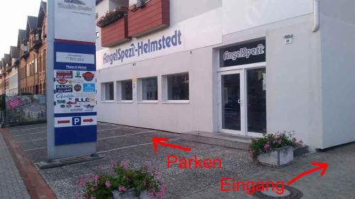 a white building with two red arrows in front of it at Fewo Helmstedt in Helmstedt