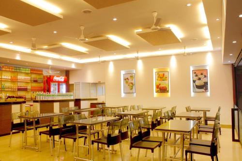 a restaurant with tables and chairs in a room at Hotel Sangam in Kanyakumari