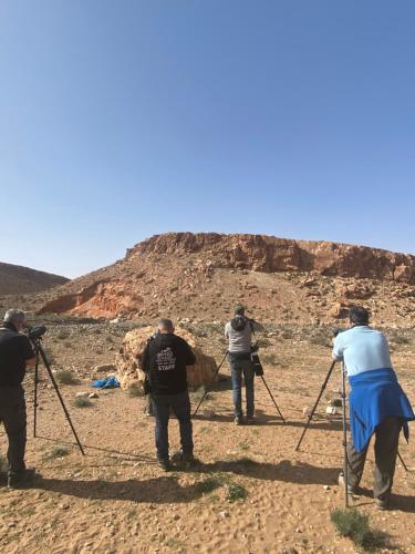 a group of people taking pictures in the desert at Riad Dades Birds in Boumalne