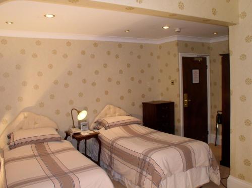 a bedroom with two beds and a door with a door at Oakwood Hall Hotel in Bingley