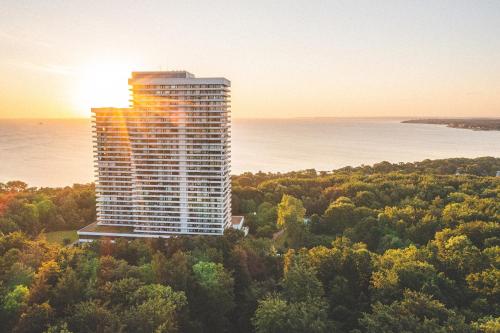 a tall building in the middle of a forest with the sunset at PLAZA Premium Timmendorfer Strand in Timmendorfer Strand