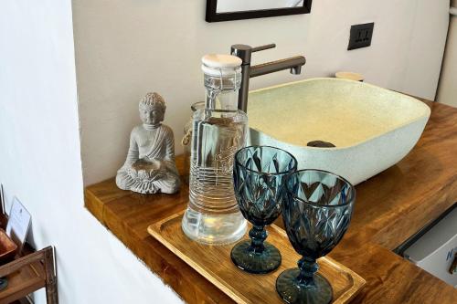 a bathroom sink with a glass bottle and two wine glasses at Txaleta de Camiguin desde 2024 in Mambajao