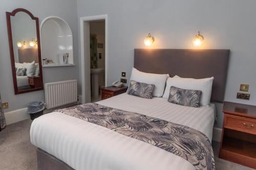 a bedroom with a large bed and a large mirror at The Lansdowne, Eastbourne in Eastbourne
