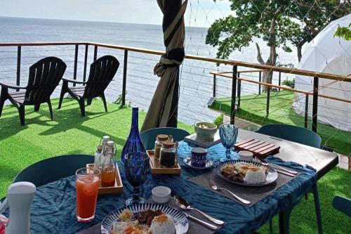 a table with food and drinks on a balcony with the ocean at Txaleta de Camiguin desde 2024 in Mambajao