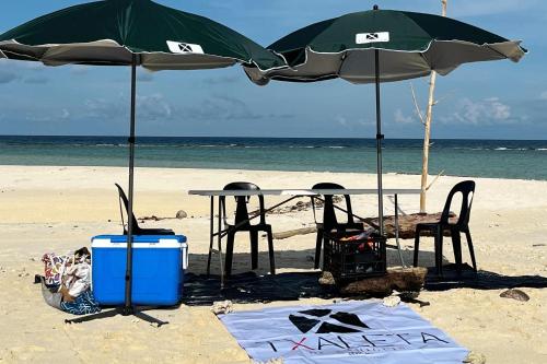 a table and chairs under umbrellas on the beach at Txaleta de Camiguin desde 2024 in Mambajao