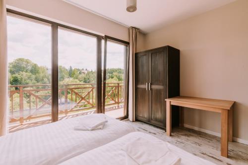a bedroom with a bed and a large window at Szumny Dwór - pokoje z łazienkami in Wetlina