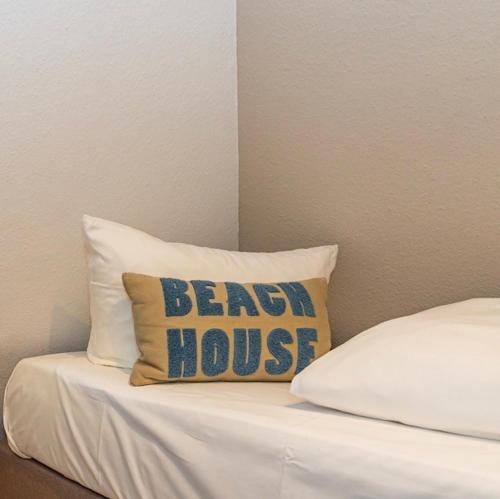 a bed with a pillow that says beach house at Söl'ring Hüs "kleiner traum rantum" in Rantum