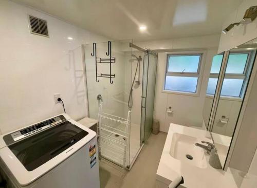 a white bathroom with a shower and a sink at Cozy 1 Bed 1 Bath Studio Kingsland - Morningside in Auckland