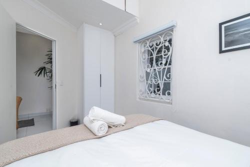 a white bedroom with a bed and a window at The Willets Boutique Hotel in Simon's Town in Simonʼs Town