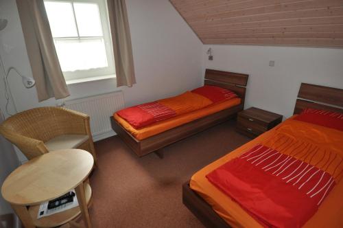 a bedroom with two beds and a chair and a window at Ferienhaus Strandläufer in Krummhörn