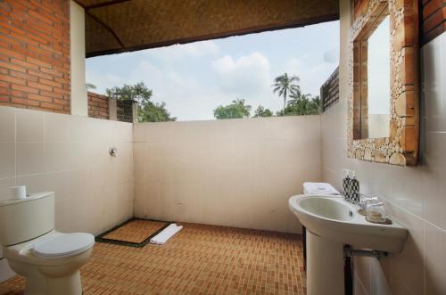 a bathroom with a toilet and a sink at Kanaka Villas by Prabha in Tampaksiring