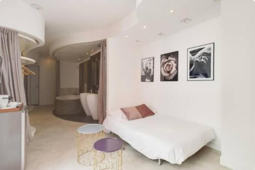 - une chambre blanche avec un lit et une baignoire dans l'établissement Magnifique appartement parisien - Marais, à Paris
