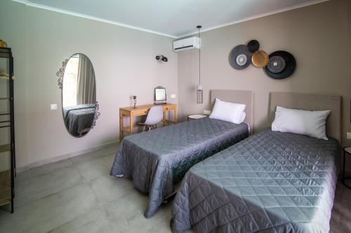 a bedroom with two beds and a desk and a mirror at Kaminia Blue Villas in Tsoukaladhes