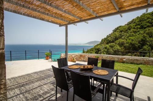 a table and chairs on a patio with a view of the ocean at Kaminia Blue Villas in Tsoukaladhes