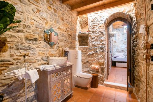 a stone bathroom with a toilet and a sink at Almond Blossom Cottage 1 in Philotium