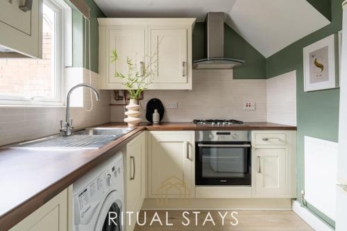 a kitchen with white cabinets and a sink at The Bracken's by Ritual Stays in Hemel Hempstead
