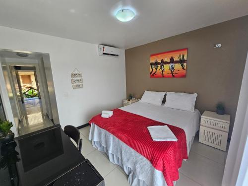 a bedroom with a bed with a red blanket and a tv at FRENTE MAR - Cumbuco - Eco Paradise in Cumbuco