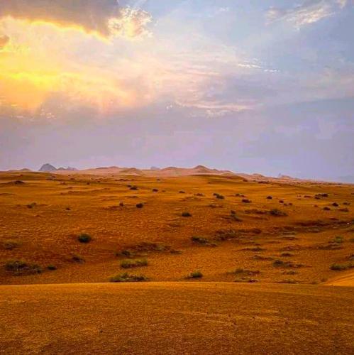 a view of a desert with a rainbow in the sky at Erg Chigaga Wil Camp in El Gouera