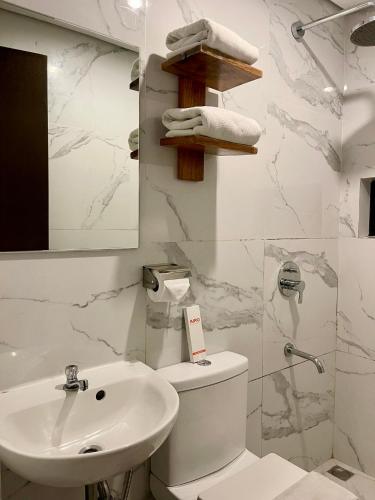 a white bathroom with a sink and a toilet at Airo Hotel Manila in Manila