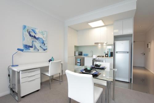 a kitchen with a desk and chairs and a refrigerator at 188 Apartments in Perth