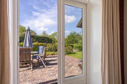 a sliding glass door leading to a patio with an umbrella at Boerderij de Borgh in Westerbork