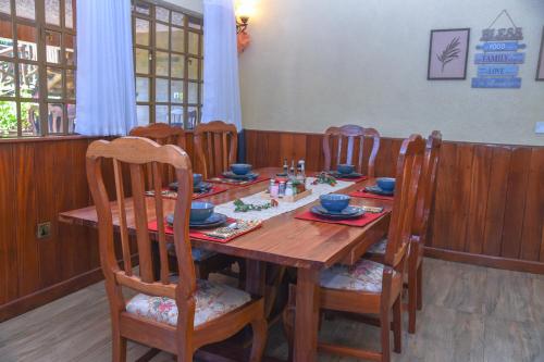 a dining room with a wooden table and chairs at Sangare Gardens- Book Now Enjoy Free Farm Tour in Mweiga
