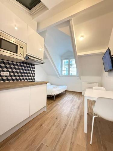 une cuisine avec des armoires blanches et une table dans une pièce dans l'établissement Studio in the 16th, à Paris