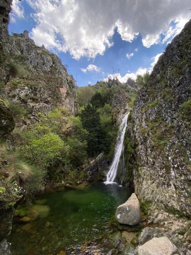a waterfall in a canyon with a pool of water at Abrigo das Penhas in Manteigas