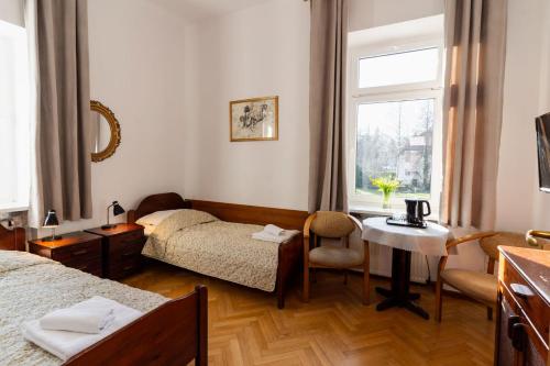 pokój z dwoma łóżkami, stołem i oknem w obiekcie Hotel Europa w Polanicy Zdroju
