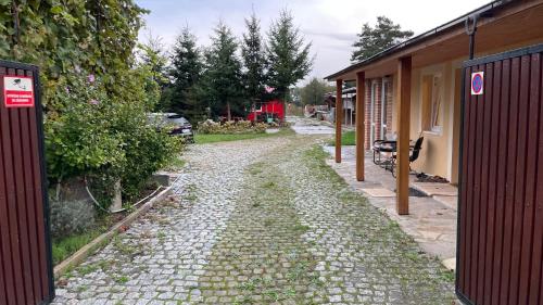 a cobblestone path next to a house with a driveway at Domek na statku in Klipec