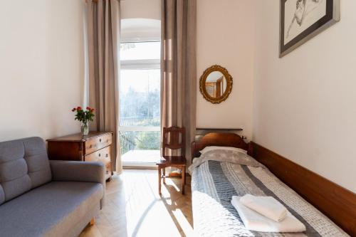 a bedroom with a bed and a couch and a window at Hotel Europa in Polanica-Zdrój