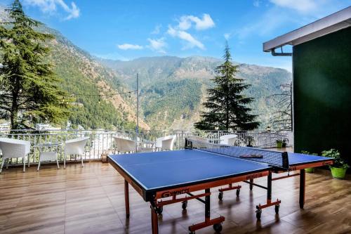 a ping pong table on a balcony with a view of mountains at The Bunksters Mcleodganj, Dharmkot in McLeod Ganj