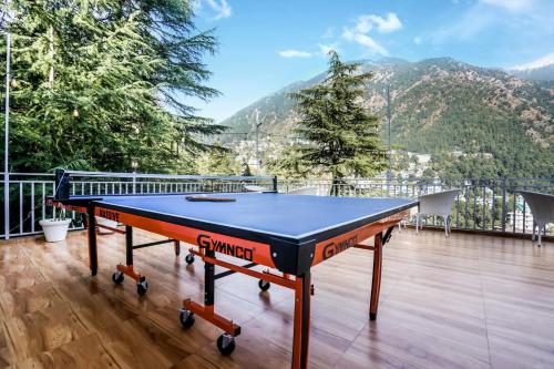 a ping pong table on a balcony with a mountain at The Bunksters Mcleodganj, Dharmkot in McLeod Ganj